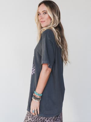 Woman wearing a dark gray t-shirt with a graphic design on a plain background