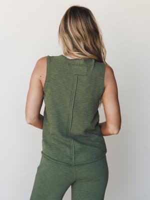 A back-view shot of a matching olive heathered tank and pants set, styled simply against a clean studio wall — the kind of easy, put-together look that blurs the line between cozy-at-home and ready-to-run-errands.