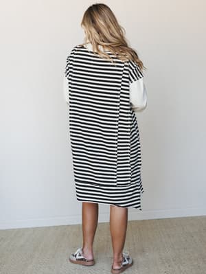 A relaxed midi dress in classic black and white stripes with contrast cream sleeves, styled with leopard print sneakers — the kind of easy, put-together look that works just as hard on a coffee run as it does at brunch.