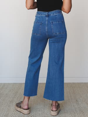 A back-view shot of wide-leg cropped jeans in a clean medium wash, styled with a black tee and leopard print platform espadrilles — the kind of effortless everyday pairing that looks like you tried just enough.
