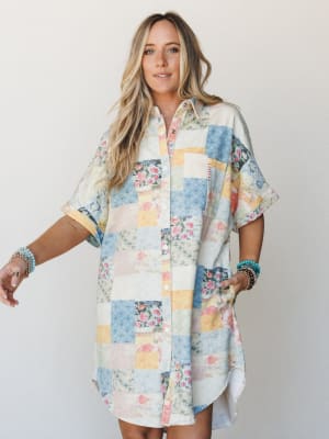 A relaxed, oversized shirt dress in a patchwork print — soft blues, blush, and butter yellow pieced together like a vintage quilt — styled with stacked turquoise bracelets for that effortlessly boho feel.
