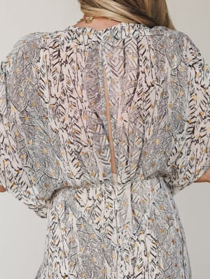 A close-up back detail shot of a printed maxi dress in cream and charcoal, featuring a keyhole back opening and voluminous sleeves — the feather-like print with gold dot accents gives it that quietly special quality you reach for when the occasion ma