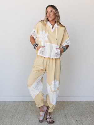 A butter yellow matching set with white crochet floral appliqués and lace paneling — the kind of outfit that makes a grocery run feel like a vacation.