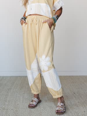 A butter yellow jogger set styled with layered beaded bracelets and buckle sandals — relaxed and expressive, like a Saturday that actually went the way you planned.