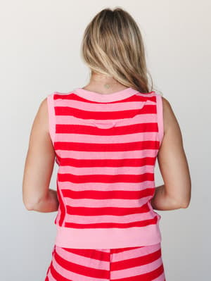 A back-facing shot of a model wearing a matching striped terry tank and shorts set in bold red and pink — the kind of cozy-meets-colorful combo that makes staying in feel intentional.