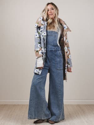 Woman wearing a floral coat over a denim outfit with a neutral background