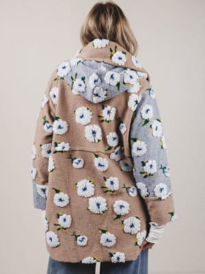 Person wearing a floral-patterned coat with a neutral background