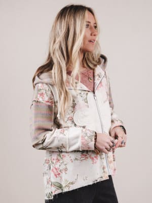 Woman wearing a floral jacket with striped sleeves on a plain background