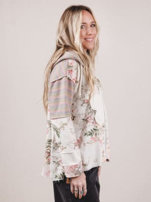 Woman wearing a floral blouse with a striped cardigan on a plain background