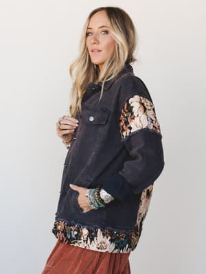 A washed navy denim jacket with tapestry patchwork panels on the sleeves and hem styled over a rust corduroy skirt — the kind of piece that looks like it came from someone's really cool vintage collection.
