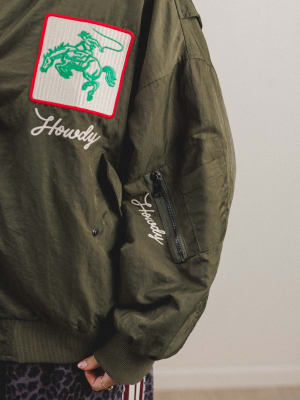 Green jacket with embroidered patch and text on a plain background