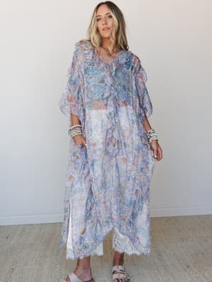 A flowy, sheer floral kimono in periwinkle blue layered over white wide-leg pants with lace trim — the kind of outfit that makes a beach town errand feel like a whole moment.