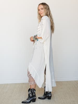 A flowy cream kimono duster with silver stud detailing is styled over a blush lace slip, grounded by embroidered black cowboy boots and stacked turquoise bracelets — the kind of outfit that looks effortless but was absolutely intentional.