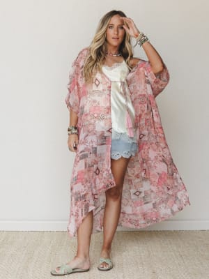 A flowy patchwork-print kimono in soft pink layers over a cream lace cami and light blue scalloped shorts — the kind of outfit that looks effortless but definitely wasn't an accident.