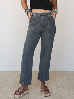 Washed charcoal wide-leg pants styled with a black crop top, stacked bead bracelets, and leopard espadrille sandals — the kind of effortless outfit that looks like you tried just enough.