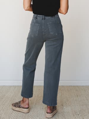 Shot from the back, this model wears faded charcoal wide-leg pants with oversized patch pockets, paired with a black tee and leopard-print espadrille flatforms — the kind of effortless everyday look that gets better the longer you wear it.