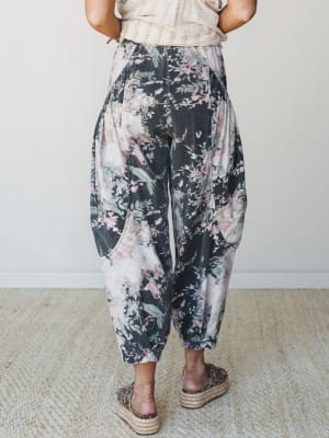 A back-view shot of relaxed barrel-leg pants in a moody dark floral print, styled with a cream crochet top and leopard espadrille platforms — the kind of outfit that looks effortless but definitely wasn't an accident.