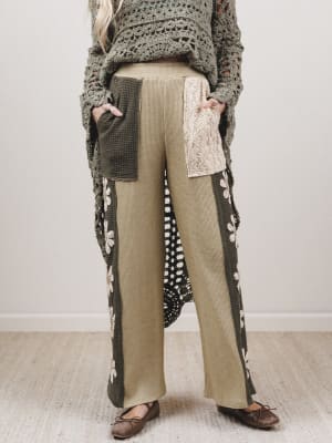 Person wearing a long, patterned cardigan over a textured top with wide-leg pants on a neutral background