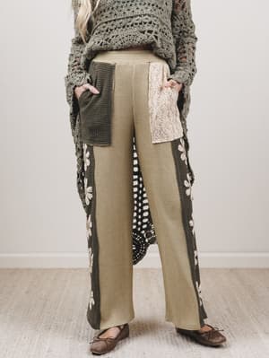 Person wearing a long, patterned cardigan over a textured top with wide-leg pants on a neutral background