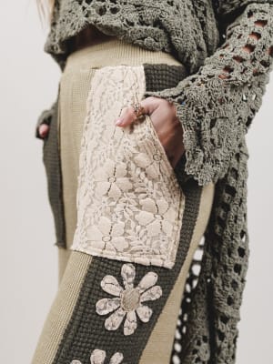 Close-up of a person wearing a textured sweater with floral patterns on a neutral background