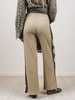 Person wearing beige ribbed pants and a patterned sweater in a minimal indoor setting.
