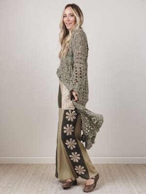 Woman wearing a long, patterned cardigan over a dress with floral designs.