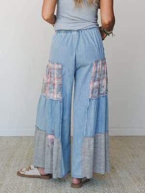 Shot from behind, these wide-leg chambray pants steal the show with patchwork plaid panels, frayed seams, and a knit hem tier — the kind of pants that feel like a vintage find but fit like they were made for you.