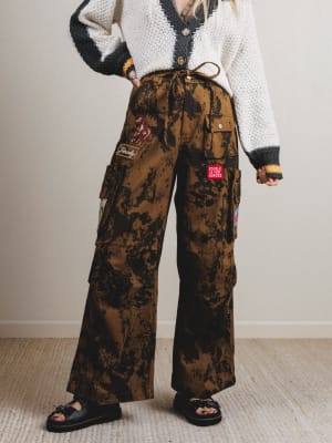 Person wearing camouflage cargo pants with patches indoors