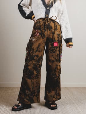 Person wearing camouflage cargo pants with patches indoors
