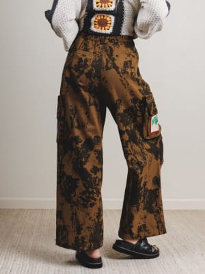 Person wearing camouflage cargo pants with a plain background