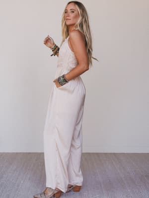 Woman wearing a white jumpsuit with a plain background