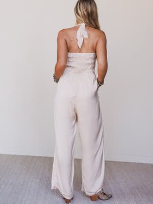 Woman wearing a strapless white jumpsuit with a plain background