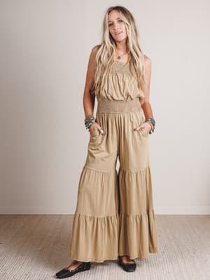Woman wearing a beige tiered dress against a plain background