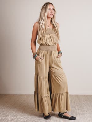 Woman wearing a beige jumpsuit with a plain background