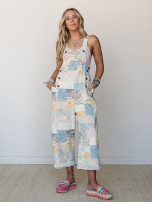A patchwork denim overall in soft pastels styled over a blush pink lace tank, worn with rainbow platform sandals — the kind of outfit that looks like a vintage quilt had a really good summer.