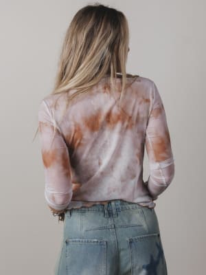 Person wearing a tie-dye shirt and jeans against a plain background