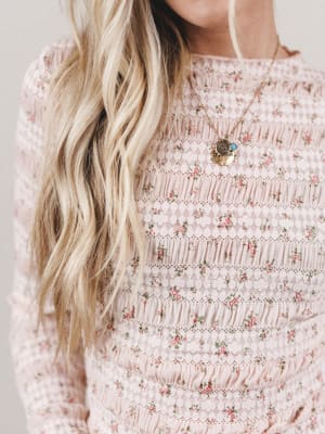 Person wearing a floral dress with a necklace, close-up on the neckline.