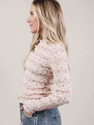 Woman wearing a textured pink sweater against a plain background