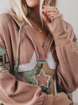 Close-up of a person wearing a patterned brown sweater with star design.