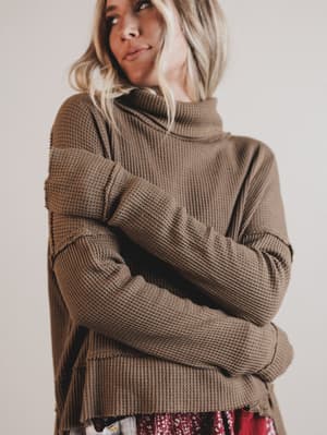 Woman wearing a brown knitted sweater against a plain background