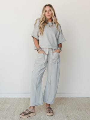 A relaxed matching set in soft dove grey — cropped sweatshirt top paired with wide-leg drawstring pants, styled with layered beaded necklaces and platform espadrilles for a casual-cool everyday look.