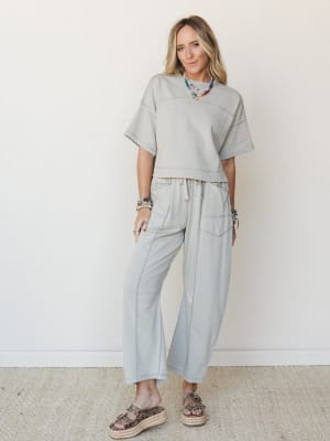 A relaxed matching set in washed dove grey — oversized crop tee and wide-leg drawstring pants styled with colorful beaded necklaces and leopard platform sandals, giving off that effortlessly put-together energy.