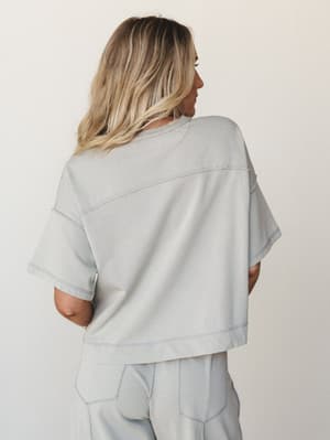 A soft, washed-grey matching set shot from the back — the boxy crop top and wide-leg pants move together in that effortless way that makes you want to wear them everywhere from a coffee run to a beach boardwalk.