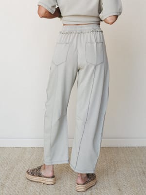 A back-view shot of wide-leg sweatpants in a soft dove grey, styled with a matching cropped sweatshirt and leopard print platform sandals — relaxed and put-together at the same time.