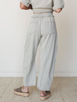 A back-view shot of wide-leg sweatpants in a soft dove grey, styled with a matching cropped sweatshirt and leopard print platform sandals — relaxed and put-together at the same time.