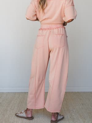 Shot from behind, this matching set in washed peachy coral pairs wide-leg sweatpants with a cropped short-sleeve sweatshirt — the kind of outfit that somehow looks intentional even when you're just wandering around the house or grabbing iced coffee.
