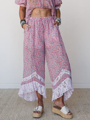 Wide-leg floral pants in a soft lilac and red ditsy print with lace ruffle hem details, styled as a matching set with a cropped top and platform espadrille sandals — the kind of outfit that makes a farmers market feel like a whole moment.