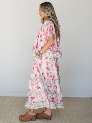 A flowy floral skirt set in cream and pink worn with brown wood clogs — the kind of outfit that feels like a garden party and a farmers market at the same time.