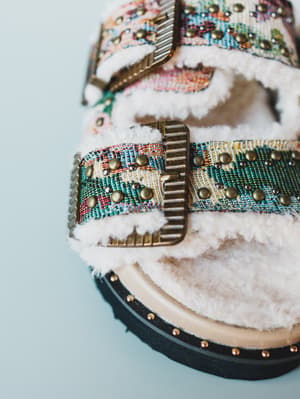 Decorative sandal with colorful pattern and white fur on a light blue background