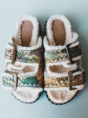 Pair of decorative slippers with fur lining on a light blue background